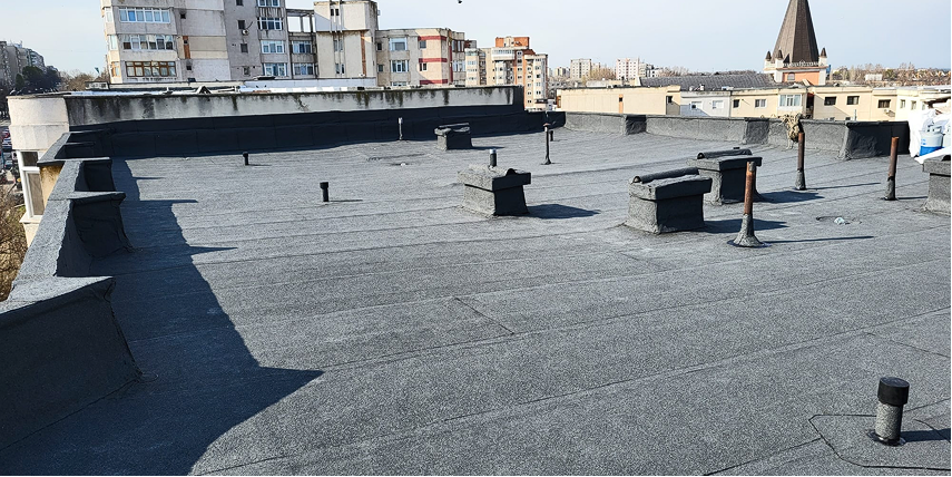 Muncitor aplicând membrană hidroizolantă pe terasa unei clădiri din Cluj-Napoca